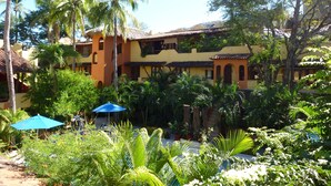 A building with a yellow facade, multiple balconies, and a thatched roof.