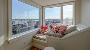 A room with a large window seat overlooking a cityscape.