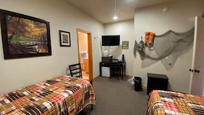 Une chambre avec deux lits, un bureau avec un ordinateur, une télévision et un panneau d’accueil.