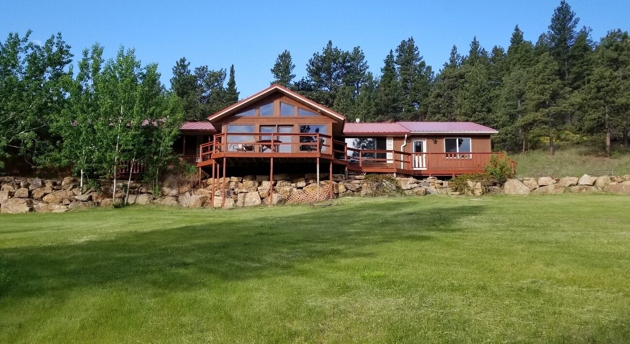 A two-story lodge with a wooden exterior, a balcony, and a stone foundation.