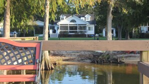 A wooden dock extending over a calm body of water with a house in the background.