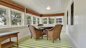 A dining area with a table and chairs, large windows, and a striped rug. - Spacious Isle of Palms Beach House with Private Pool, One Block To The Beach (Isle of Palms)