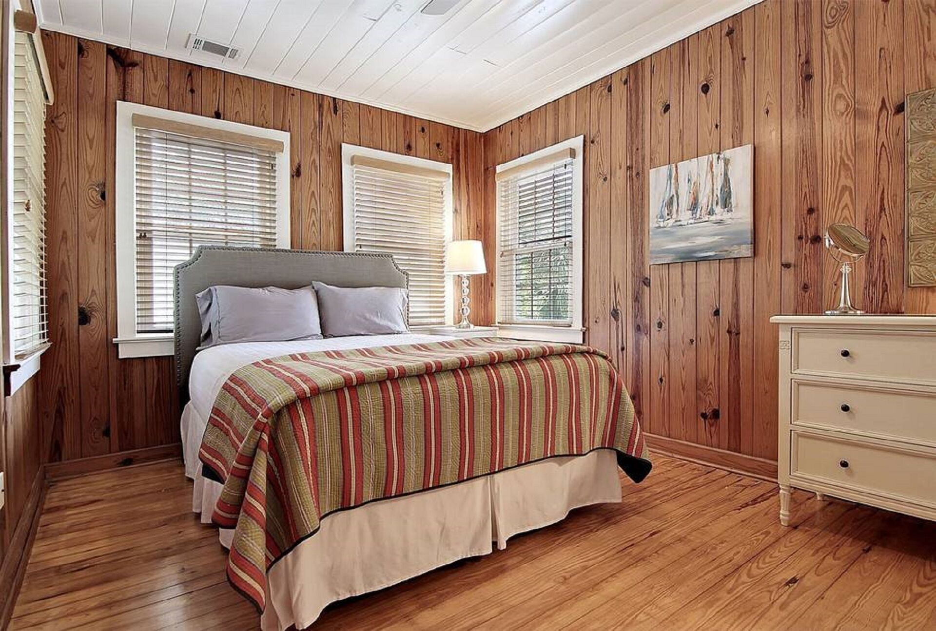 Un dormitorio con una cama, paredes de madera y un aparador.