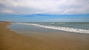 A beach with a wide sandy shore and gentle waves. - Spacious Isle of Palms Beach House with Private Pool, One Block To The Beach (Isle of Palms)