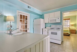 Kitchen features a central island with sink and lamp, adjacent to a refrigerator, stove, and oven.