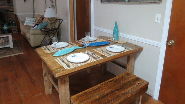 Una mesa de comedor de madera con platos, vasos y un protector de mesa con forma de pez.