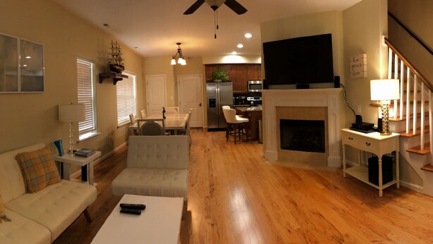 A spacious living area with a fireplace, a dining table, and a kitchen in the background.