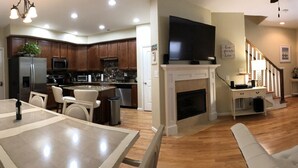A spacious living room with a fireplace, a dining area, and a kitchen with modern appliances.