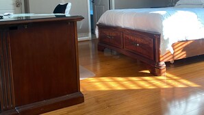 A bedroom with a wooden bed, a desk, and a door leading to another room.