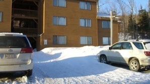 A multi-story building with a brick facade, several windows, and a visible balcony. - Rustic and cozy Walk In-Walk Out Ski Condo (Carrabassett Valley)