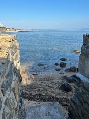 Panorama costiero con scogliere rocciose e mare calmo.