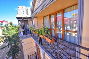 A building with a balcony, potted plants, and a view of the street. - Hotel Chao (Batumi)