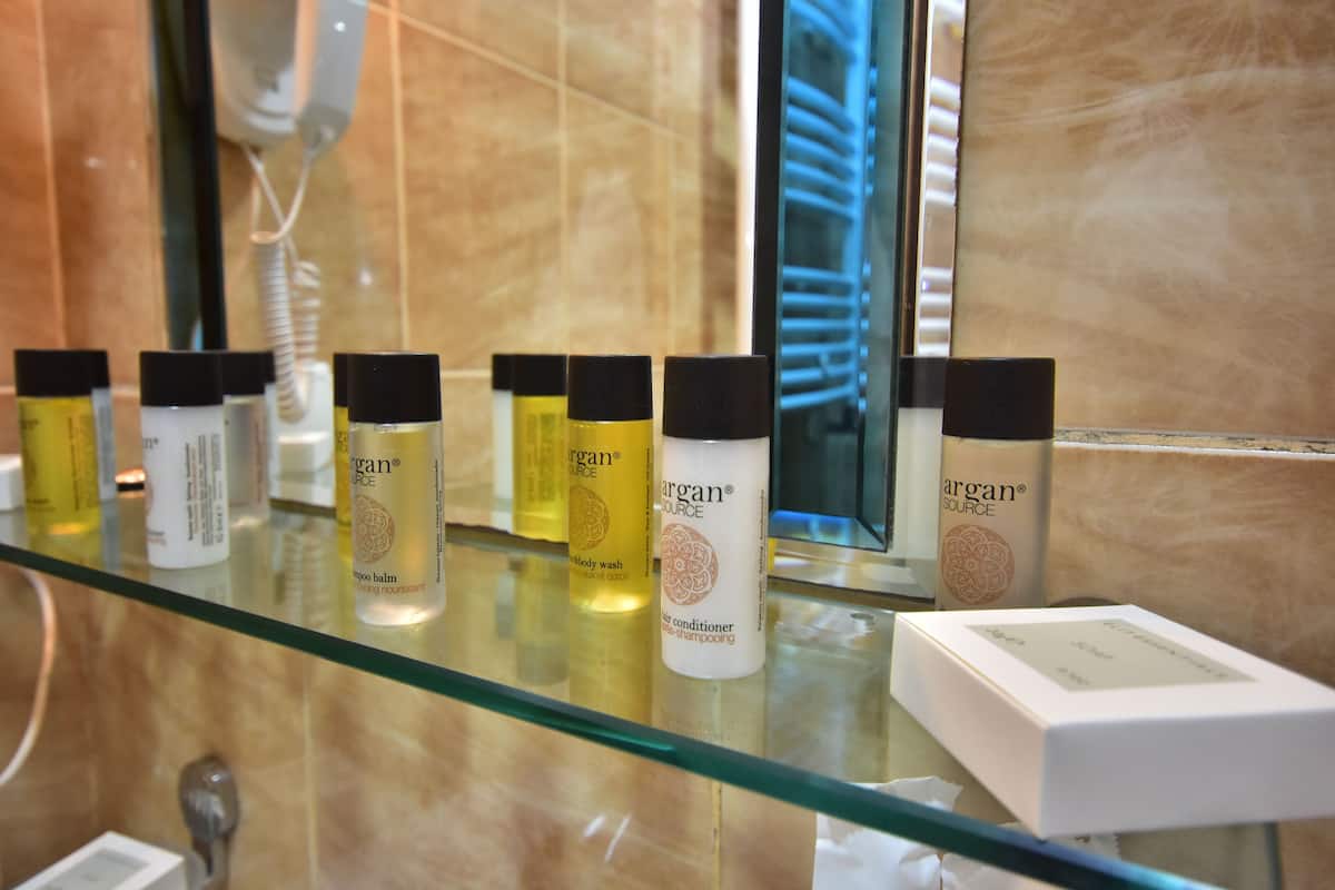 A bathroom with a glass shelf displaying various Argan Source products.