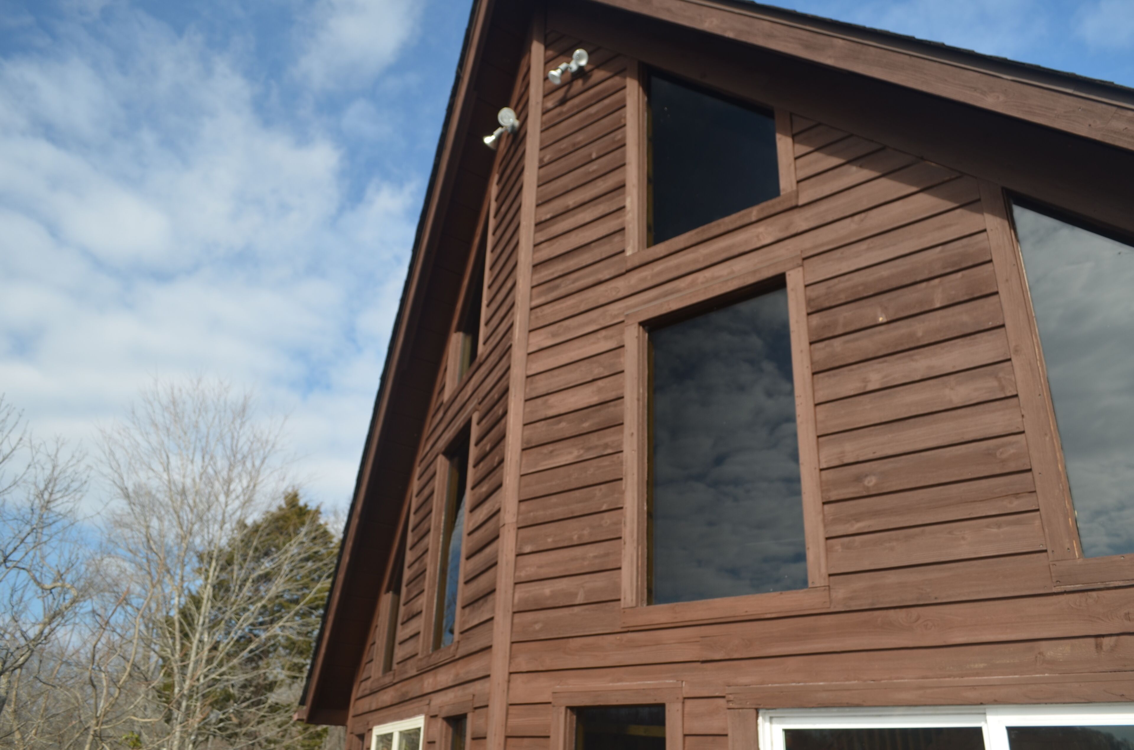 A brown wooden building with large windows and a sloped roof.