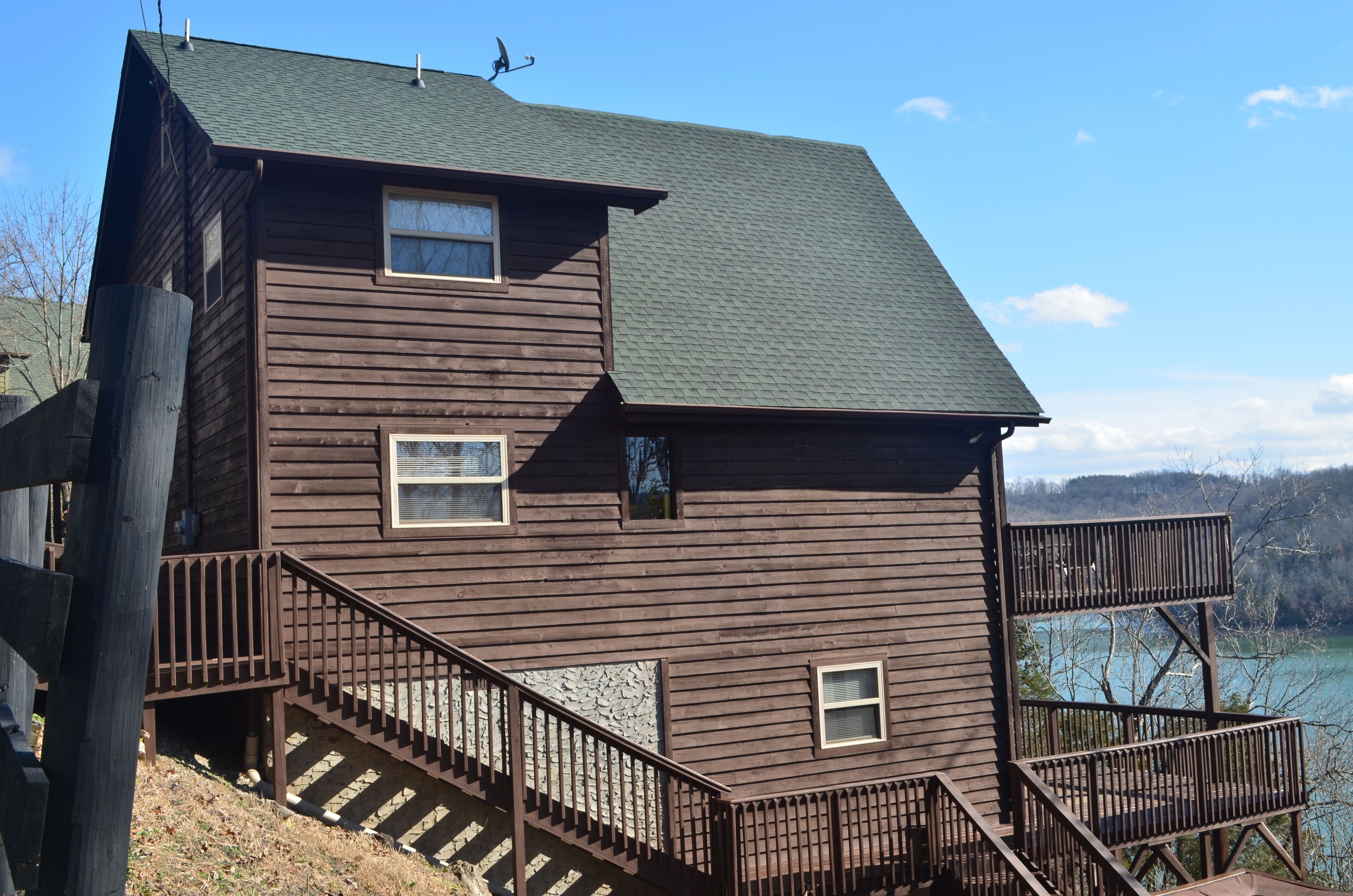 A two-story wooden cabin with a balcony and a staircase leading to the upper floor.
