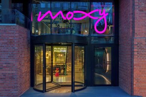 Un edificio con entrada de vidrio y un letrero de neón que dice "mozy".