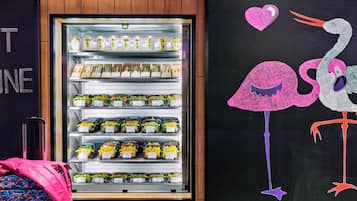 Habitación de hotel con un minibar, una maleta e ilustración de una cigüeña en la pared.