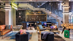 A modern lounge area with seating, tables, and a foosball table.