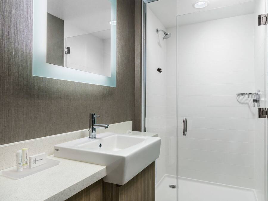 Un baño moderno con un espejo grande, un lavabo y una zona de ducha.