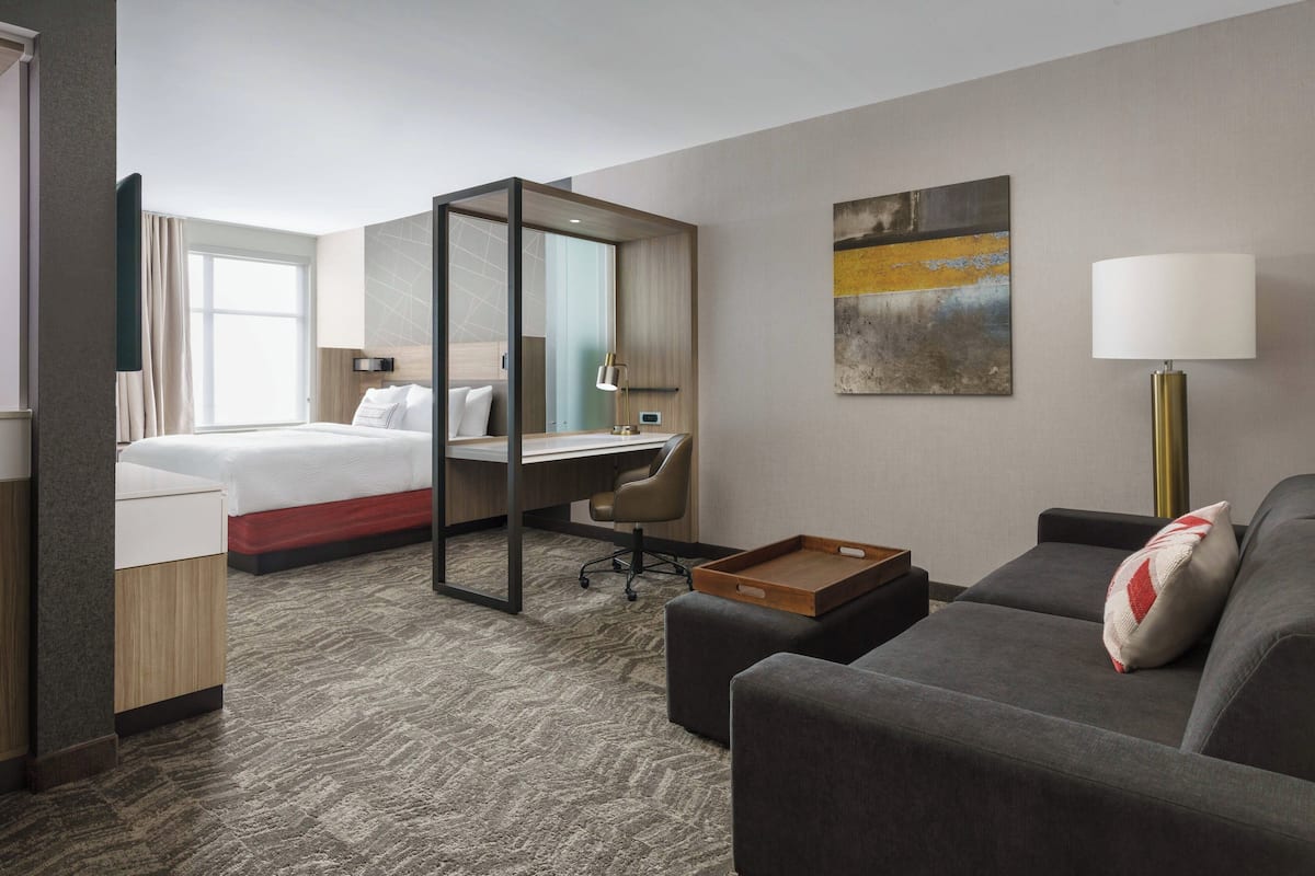 A hotel room with a bed, desk, and seating area.