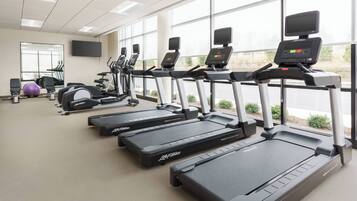 Une salle de sport équipée de tapis de course, d’appareils elliptiques et d’un vélo d’appartement.