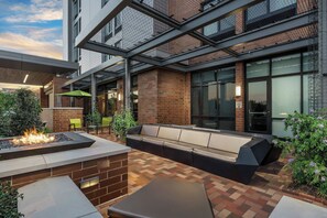 Un espace extérieur aménagé avec un foyer, des murs en briques et une structure en verre.