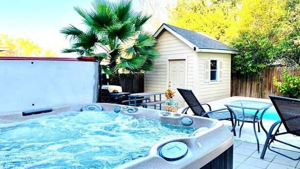 A hot tub with a wooden deck, a small shed, and a pool table.