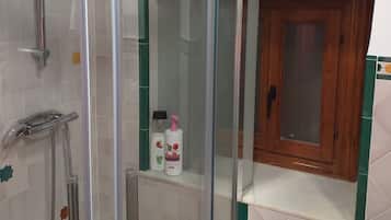 Een bad/douchecombinatie, een haardroger, badjassen, handdoeken