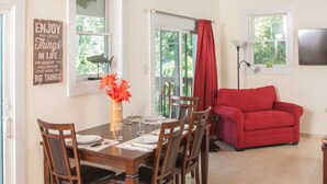 A dining area with a wooden table, chairs, and a red sofa. There are windows with curtains, a ceiling fan, and a wall-mounted TV. - Upscale, new, centrally located to all the attractions in Rincon w beach access (Rincon)