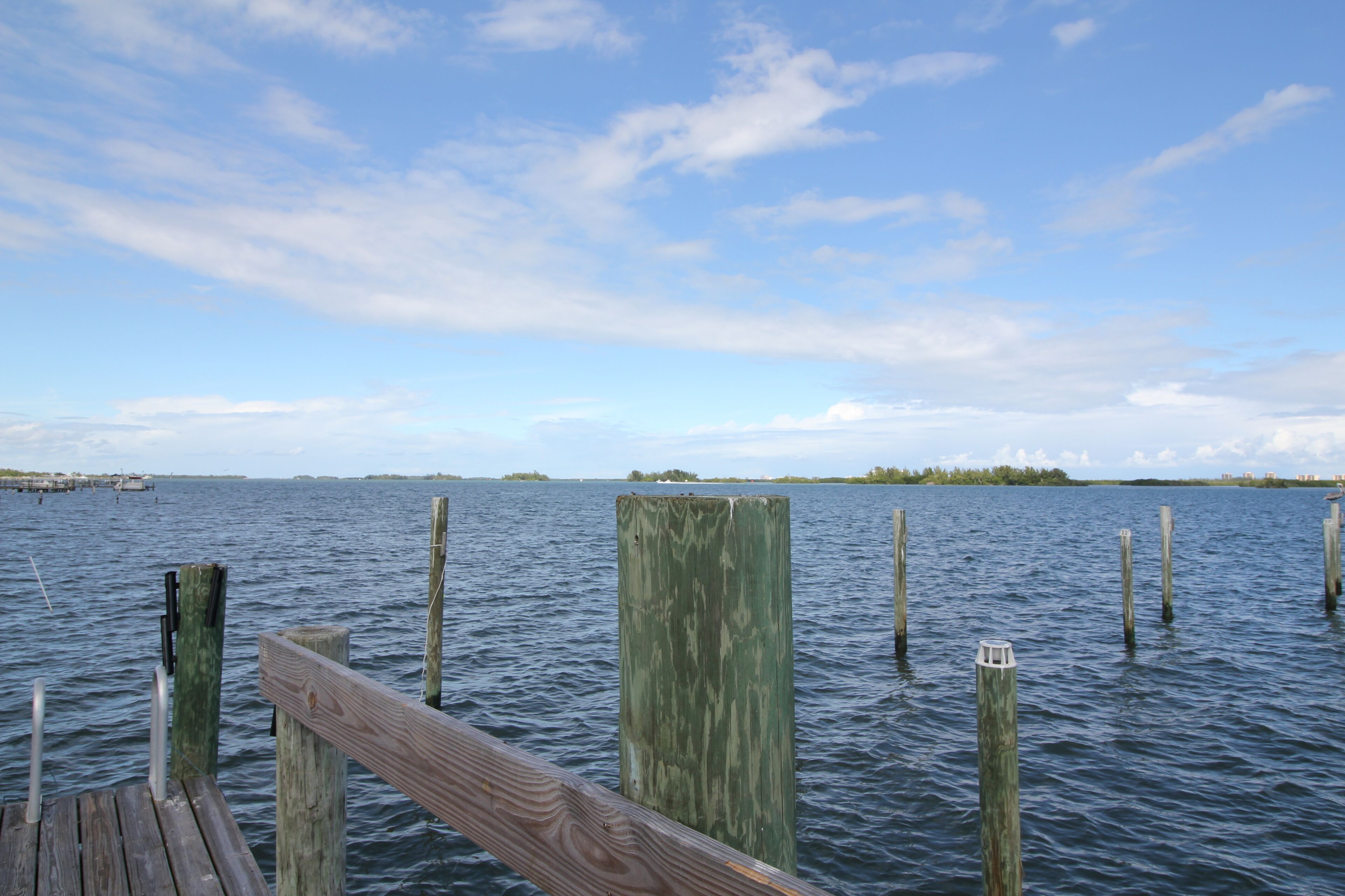 Eine hölzerne Steg, der sich in ruhiges Wasser erstreckt, mit blauem Himmel darüber.