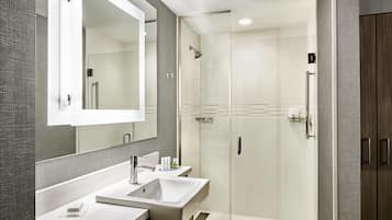 Un baño moderno con un espejo grande, dos lavamanos, una ducha y un vestidor de ducha.