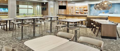 Un restaurant moderne doté de plusieurs espaces de restauration, comprenant des tables et des chaises, ainsi qu’un comptoir où est affiché le menu.