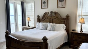 Un dormitorio con una cama grande, un ventilador de techo y dos mesitas de noche con lámparas.