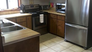 Una cocina con gabinetes de madera, un refrigerador de acero inoxidable, una estufa y un microondas.