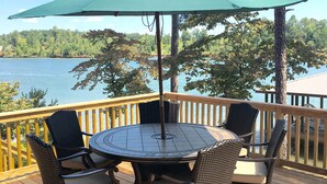 Una terraza con una mesa redonda y sillas de mimbre, con vistas a un lago.