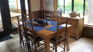 Comedor con muebles de madera, un mapa en la pared y vista a los árboles por la ventana.