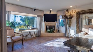 Een ruime woonkamer met een open haard, een grote flatscreen televisie en een comfortabele zithoek.