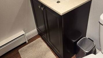Une salle de bain avec un lavabo blanc, des meubles sombres, un miroir et des toilettes.