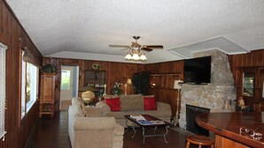 A cozy living room with a fireplace, wooden furniture, and a television. - The Lodge, cozy one bedroom King Cottage on the Indian River Lagoon (Fort Pierce)