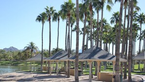Zona de playa con palmeras, un lago y estructuras cubiertas.