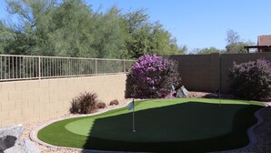 Un campo de mini golf con un área de juego verde, una bandera y un muro de ladrillo.