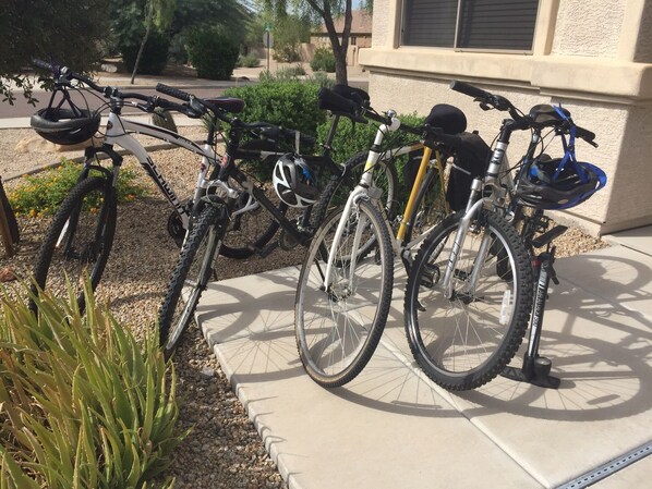 Bicycles parked outside a building with a concrete sidewalk and small plants. - Beautiful Estrella Mountain Home with Private Pool and Putting Green (Goodyear)