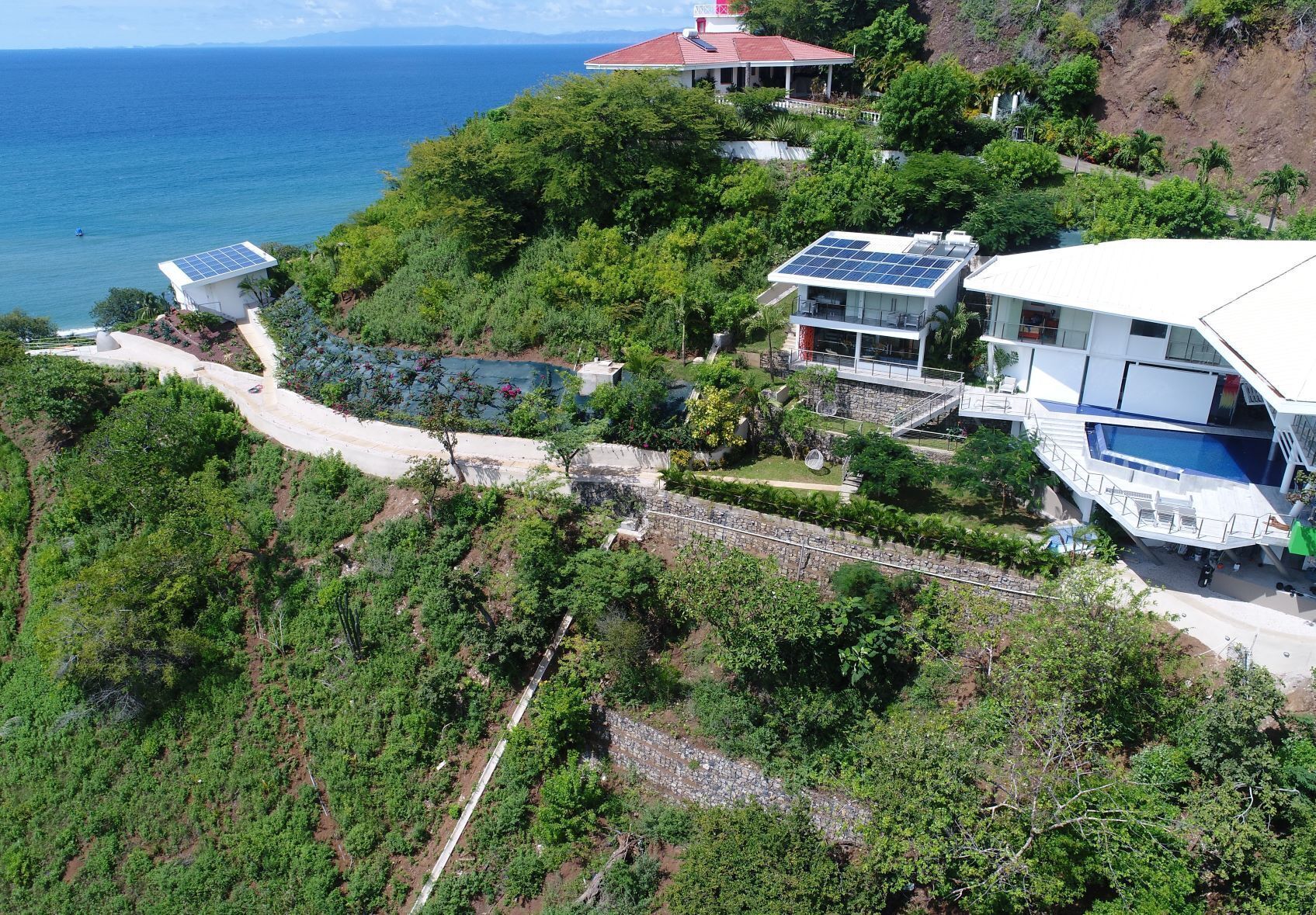 A coastal property with solar panels, a swimming pool, and a view of the ocean.