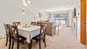 A dining area with a table and chairs, a sofa, and a ceiling light fixture.