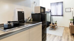 A compact kitchen with a stove, sink, and microwave. - Trip Pod Chiyo A (Fukuoka)