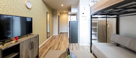 Un salon moderne avec un téléviseur à écran plat, un canapé, un meuble en bois et une petite plante.