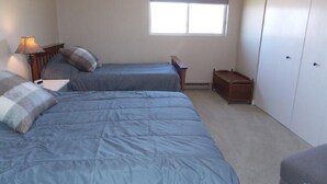 Een slaapkamer met twee bedden, een raam, een nachtkastje en een kledingkast.