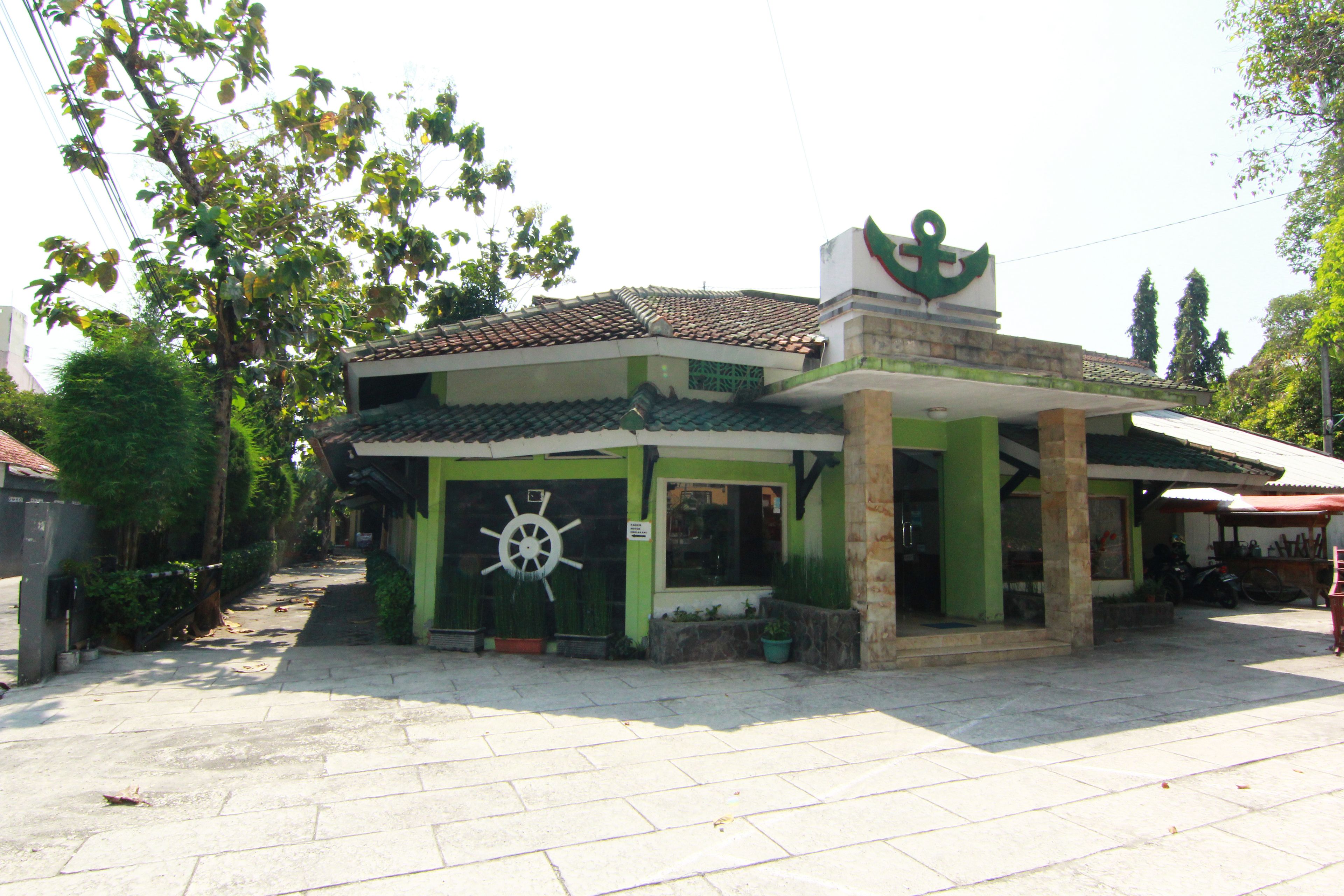 A building with a green facade, a tiled roof, and a large anchor symbol on the front.