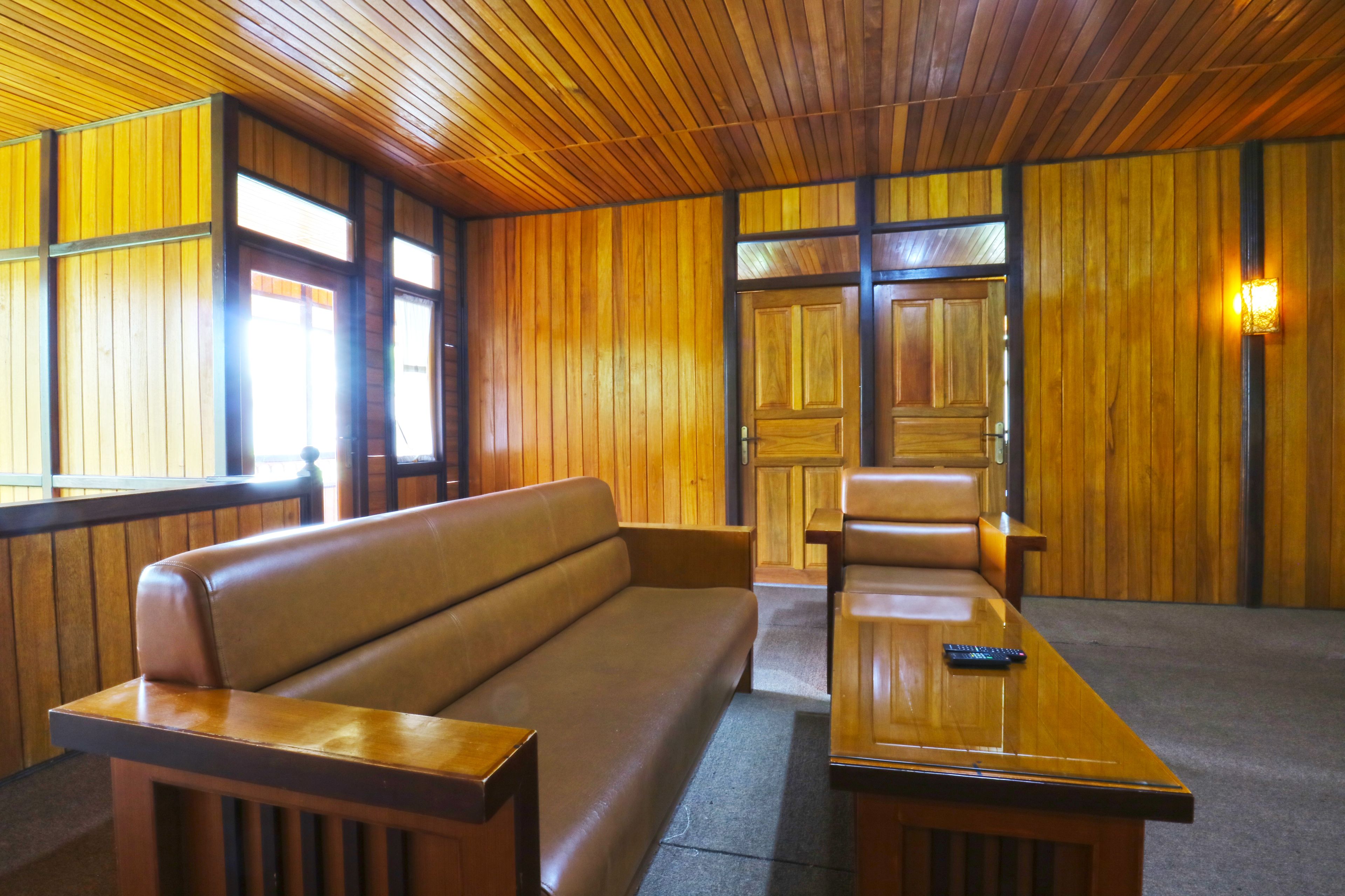 Una habitación con paredes de madera, una banca, una mesa y una puerta.