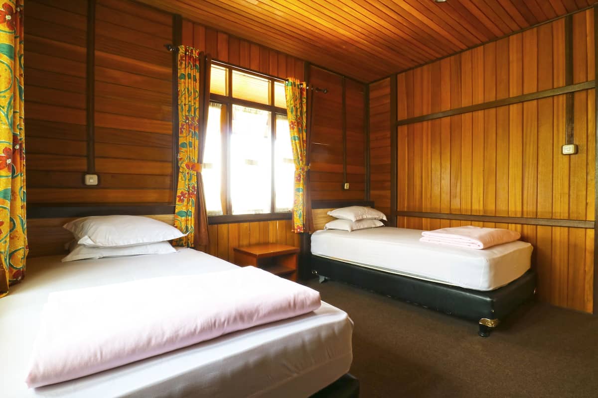 Une chambre avec deux lits, des murs en bois et une fenêtre avec des rideaux.